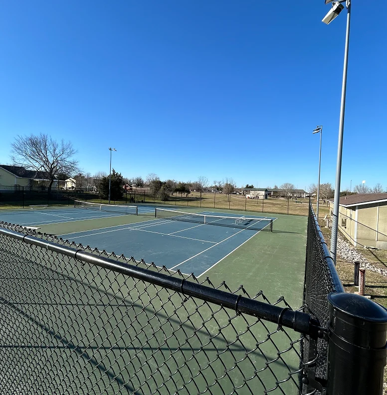 Black chain link fence surrounding two court tennis court in Austin, Texas.