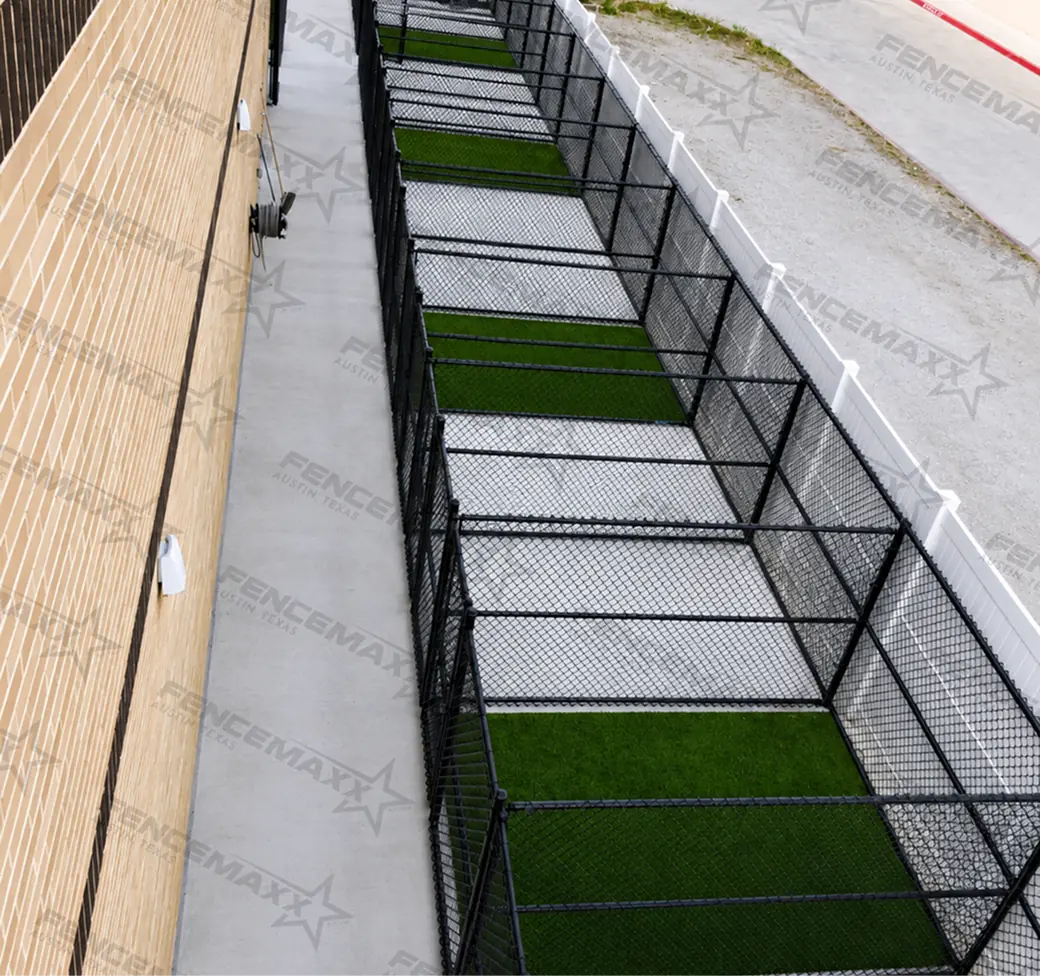 Black vinyl-coated chain link enclosures with turf flooring at a pet boarding facility