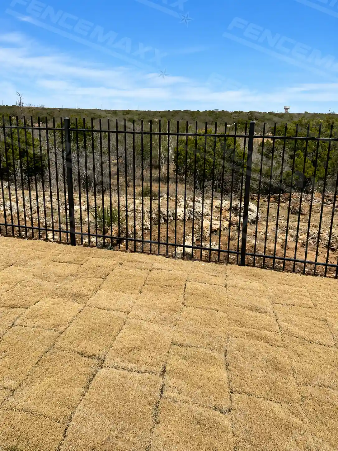An open top steel fence around freshly laid sod grass.