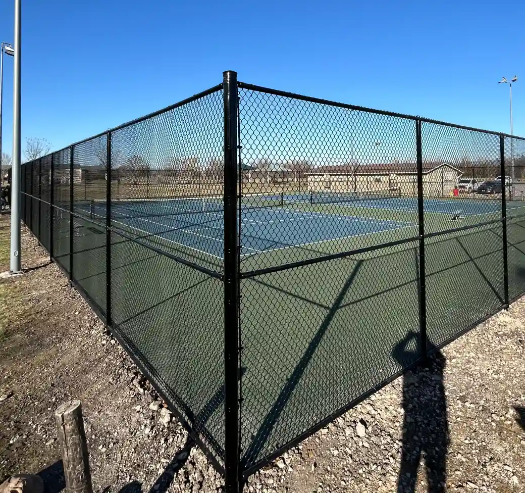 Tall black chain link fence enclosing a tennis court